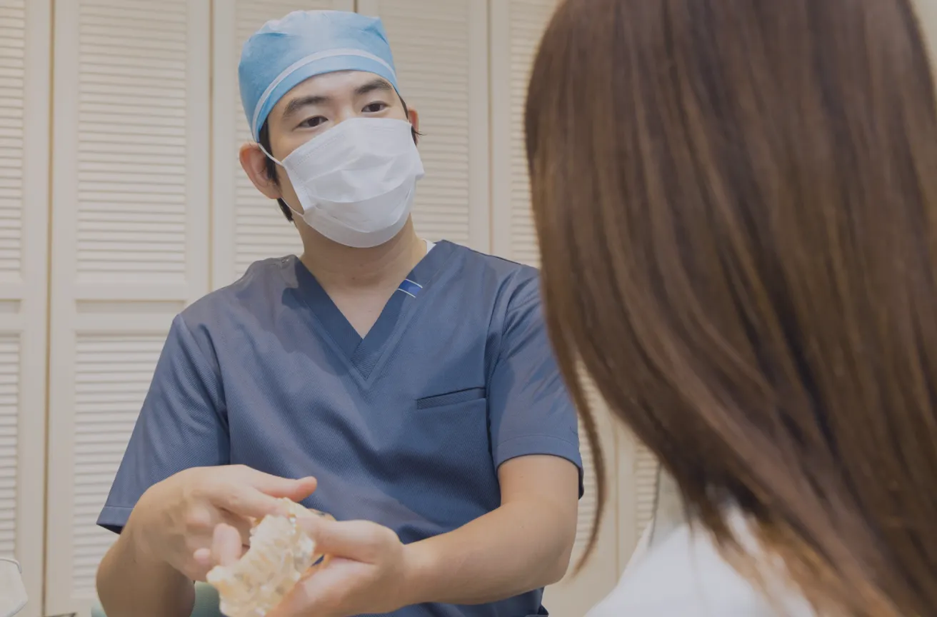 歯の模型を手にして患者さまに説明している医師